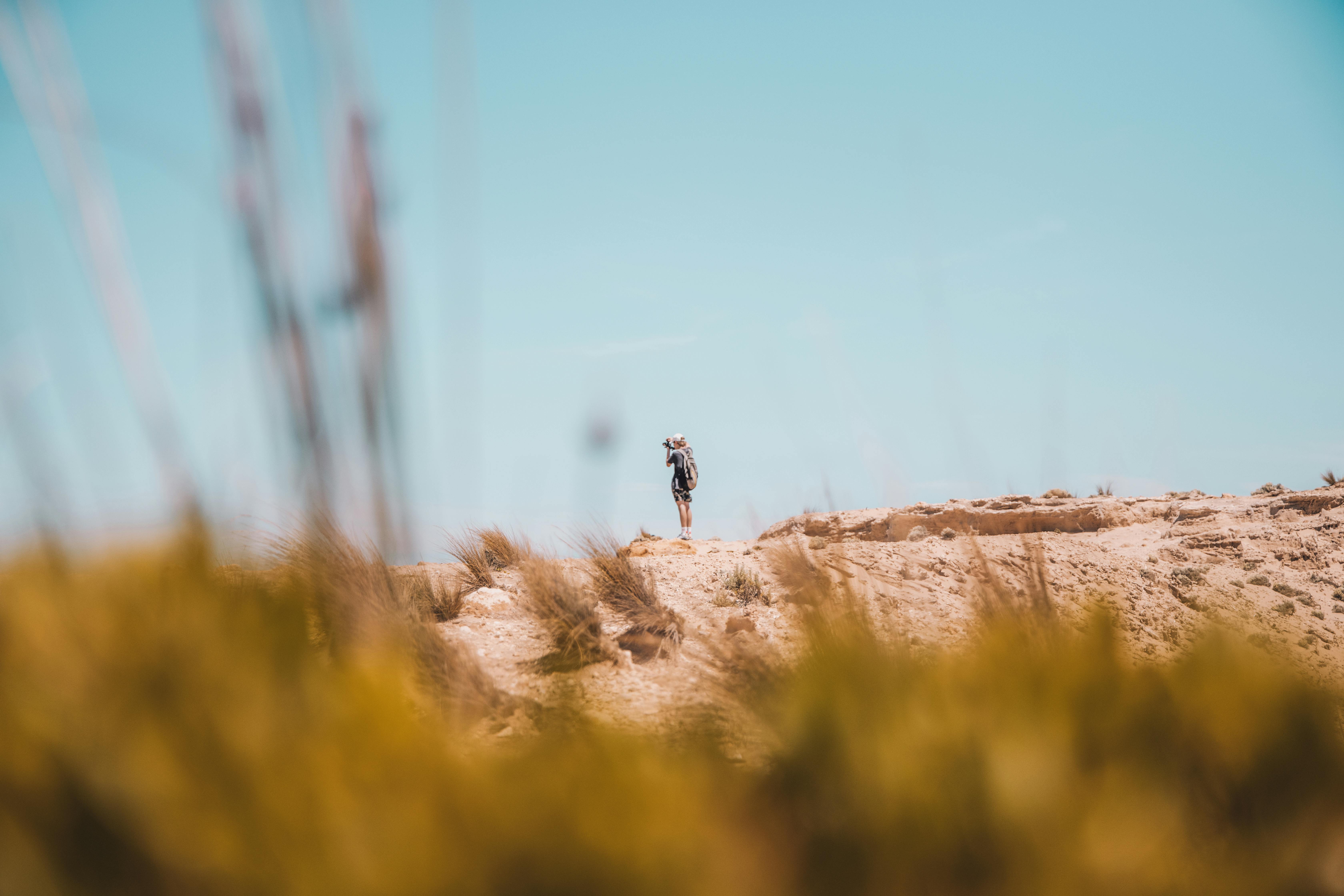 person wearing black jacket standing on a rock